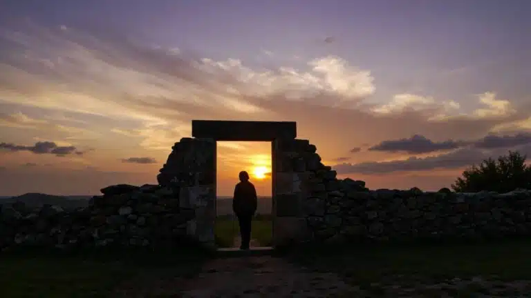 Silhouette in stone archway at sunset symbolizing God knows your name even when unnamed